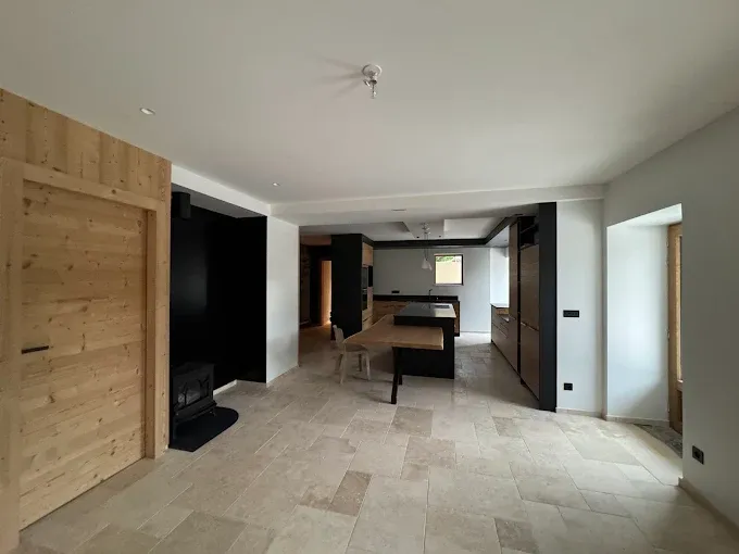 Cuisine moderne avec murs noirs, bois naturel et carrelage beige, réalisée par Deniz Peinture à Chambéry, spécialiste en peinture intérieure et finitions haut de gamme.